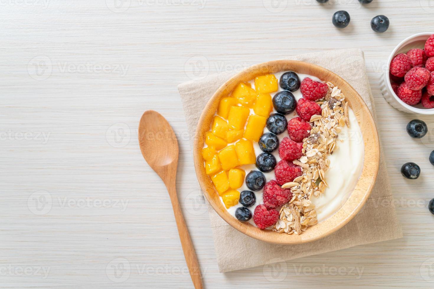 ciotola di yogurt fatta in casa con lampone, mirtillo, mango e muesli - stile alimentare sano foto