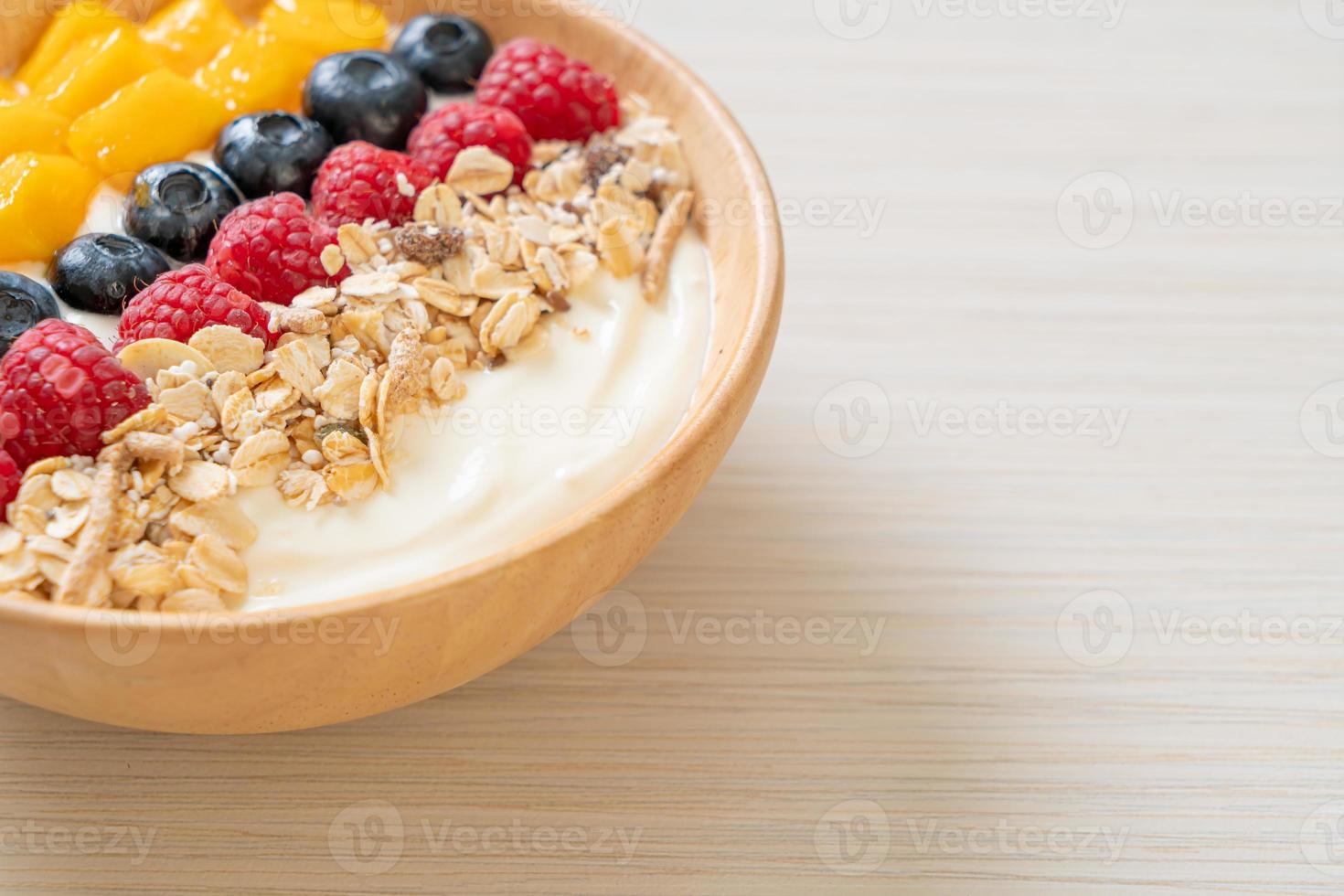 ciotola di yogurt fatta in casa con lampone, mirtillo, mango e muesli - stile alimentare sano foto
