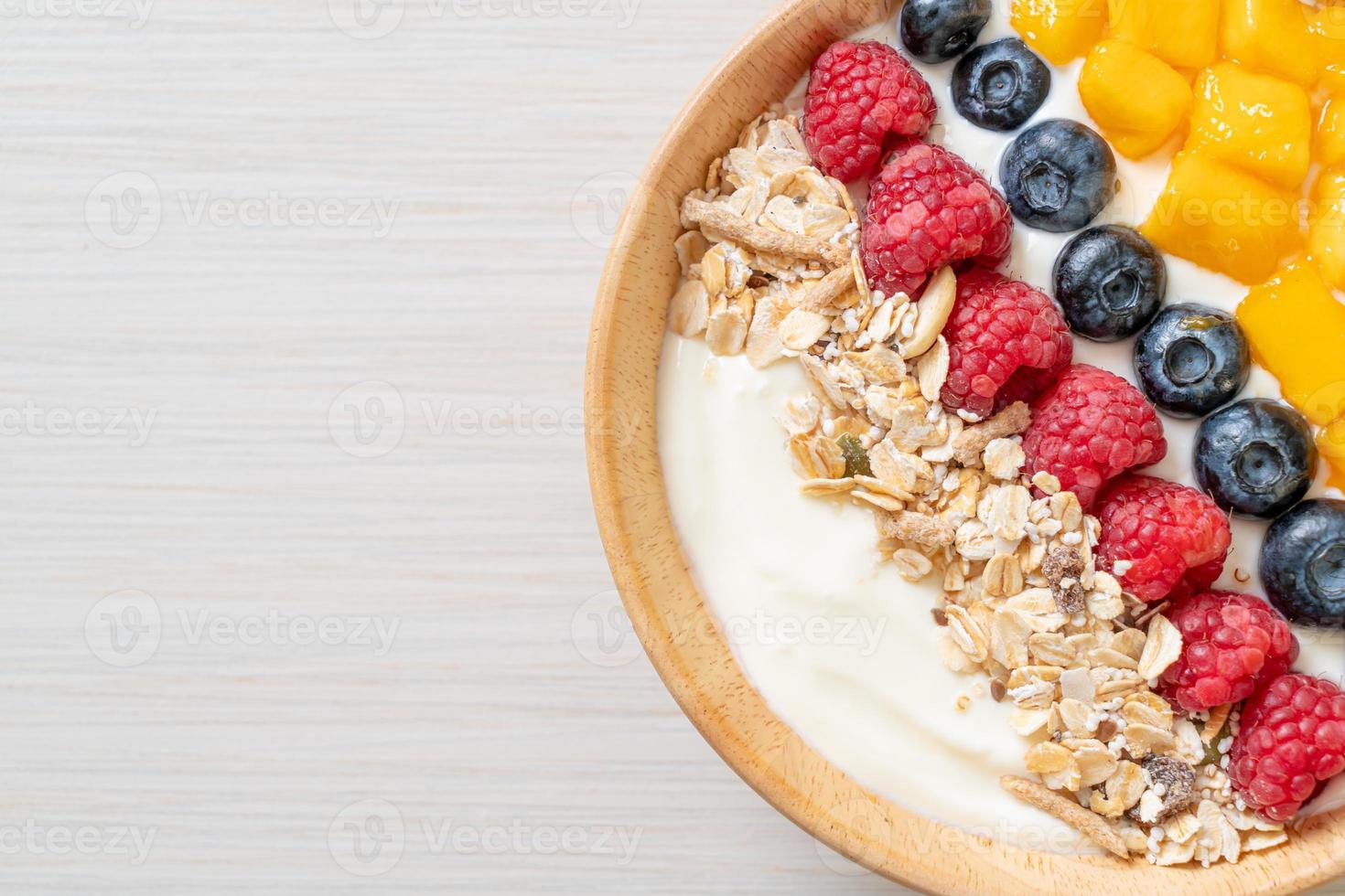 ciotola di yogurt fatta in casa con lampone, mirtillo, mango e muesli - stile alimentare sano foto