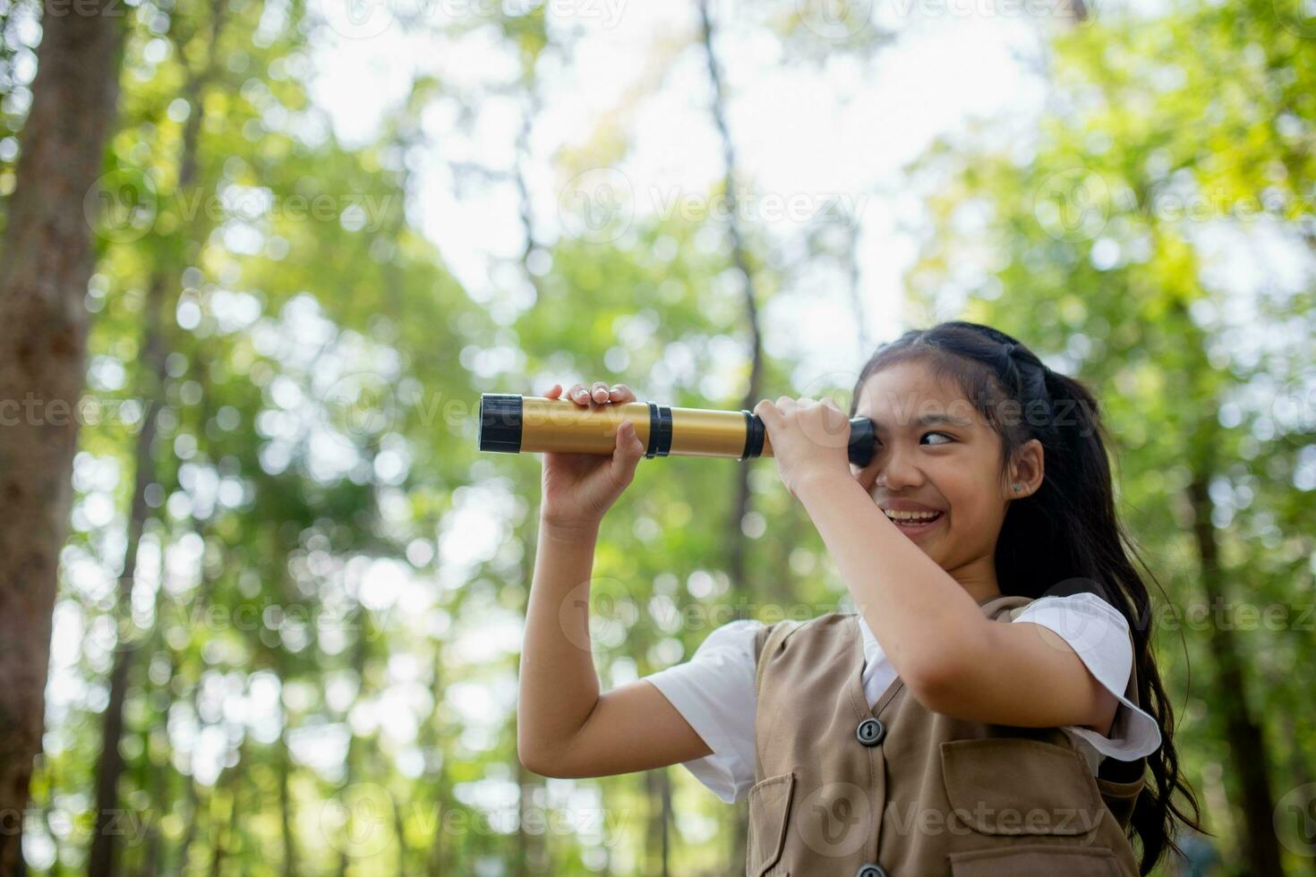 contento poco asiatico ragazze guardare avanti e sorridente bambino con il binocolo nel il parco. viaggio e avventura concetto. libertà, vacanza foto