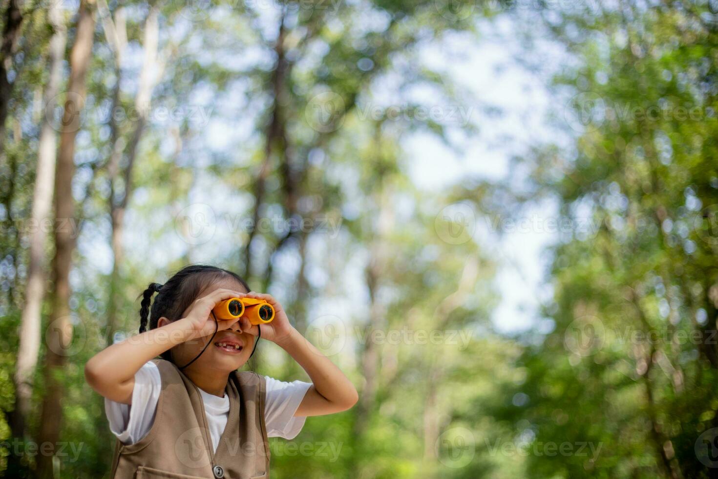 contento poco asiatico ragazze guardare avanti e sorridente bambino con il binocolo nel il parco. viaggio e avventura concetto. libertà, vacanza foto