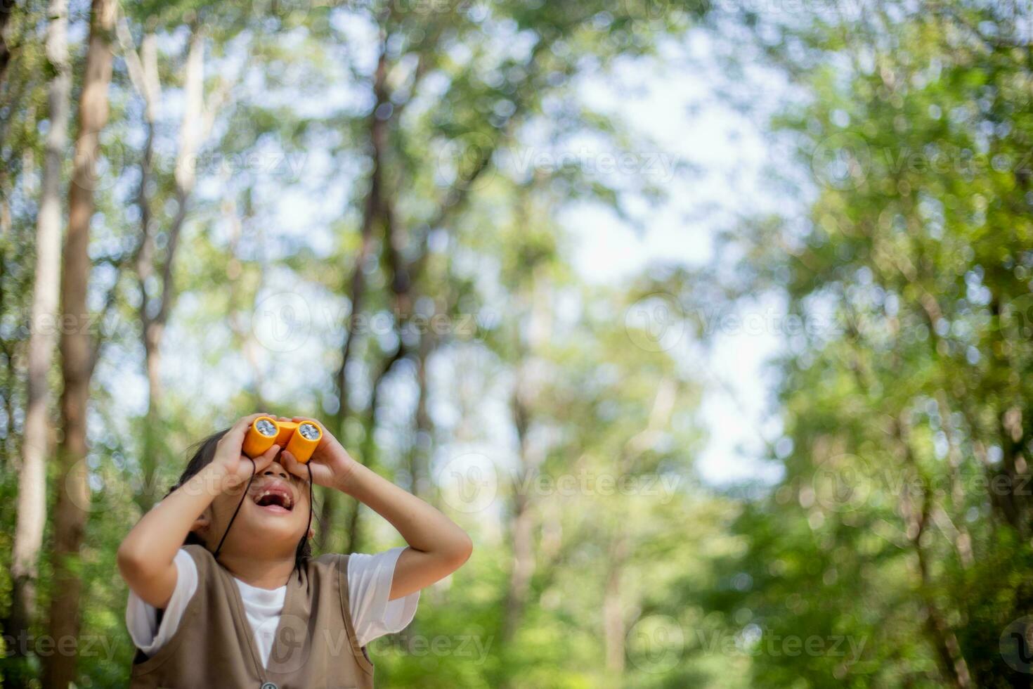 contento poco asiatico ragazze guardare avanti e sorridente bambino con il binocolo nel il parco. viaggio e avventura concetto. libertà, vacanza foto