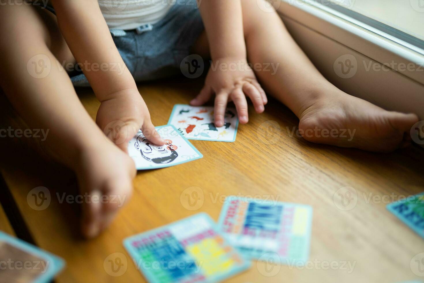 un' piccolo bambino giochi con sviluppando carte a partire dal un' tavola gioco foto