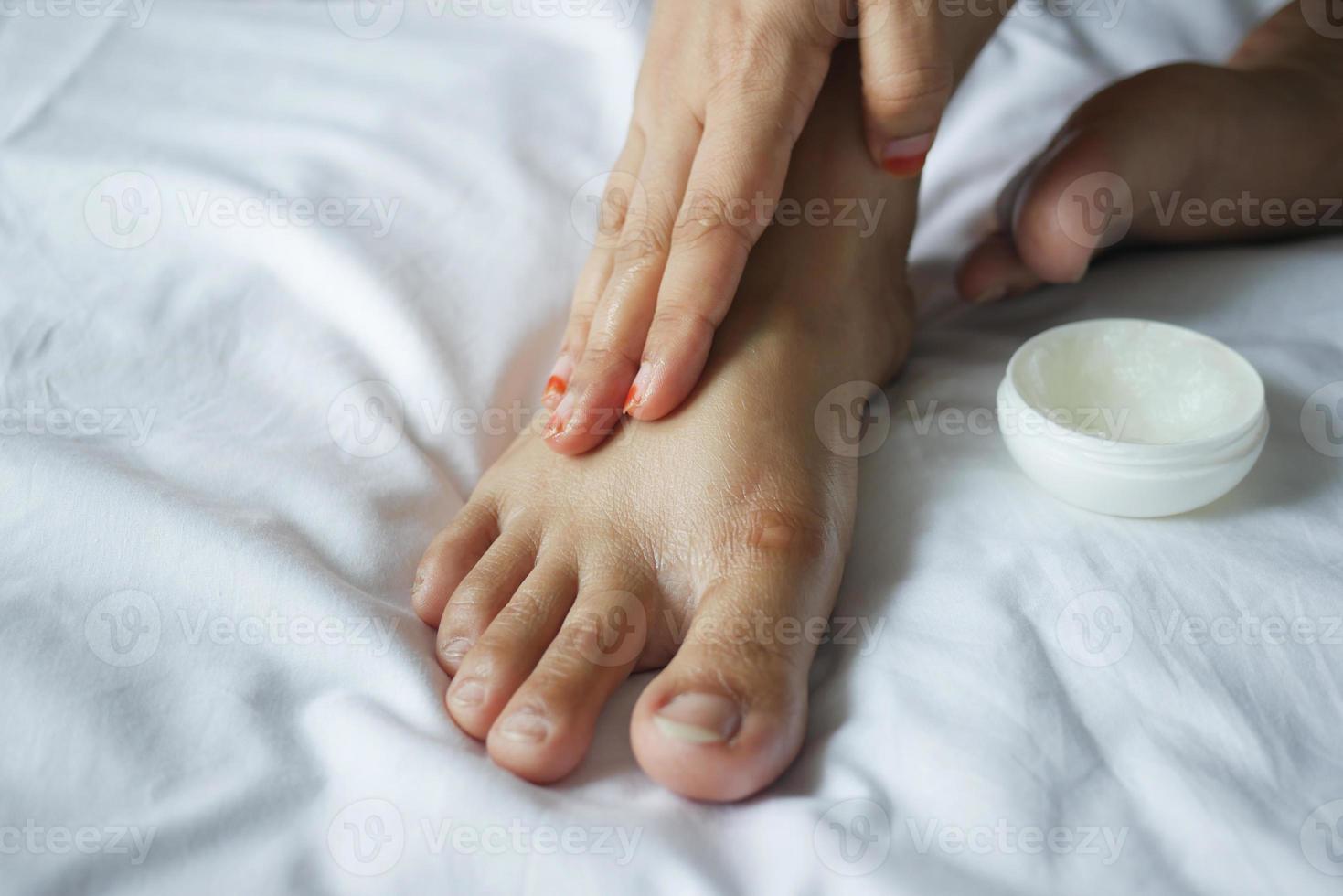 donna che applica vaselina sui piedi sul letto foto