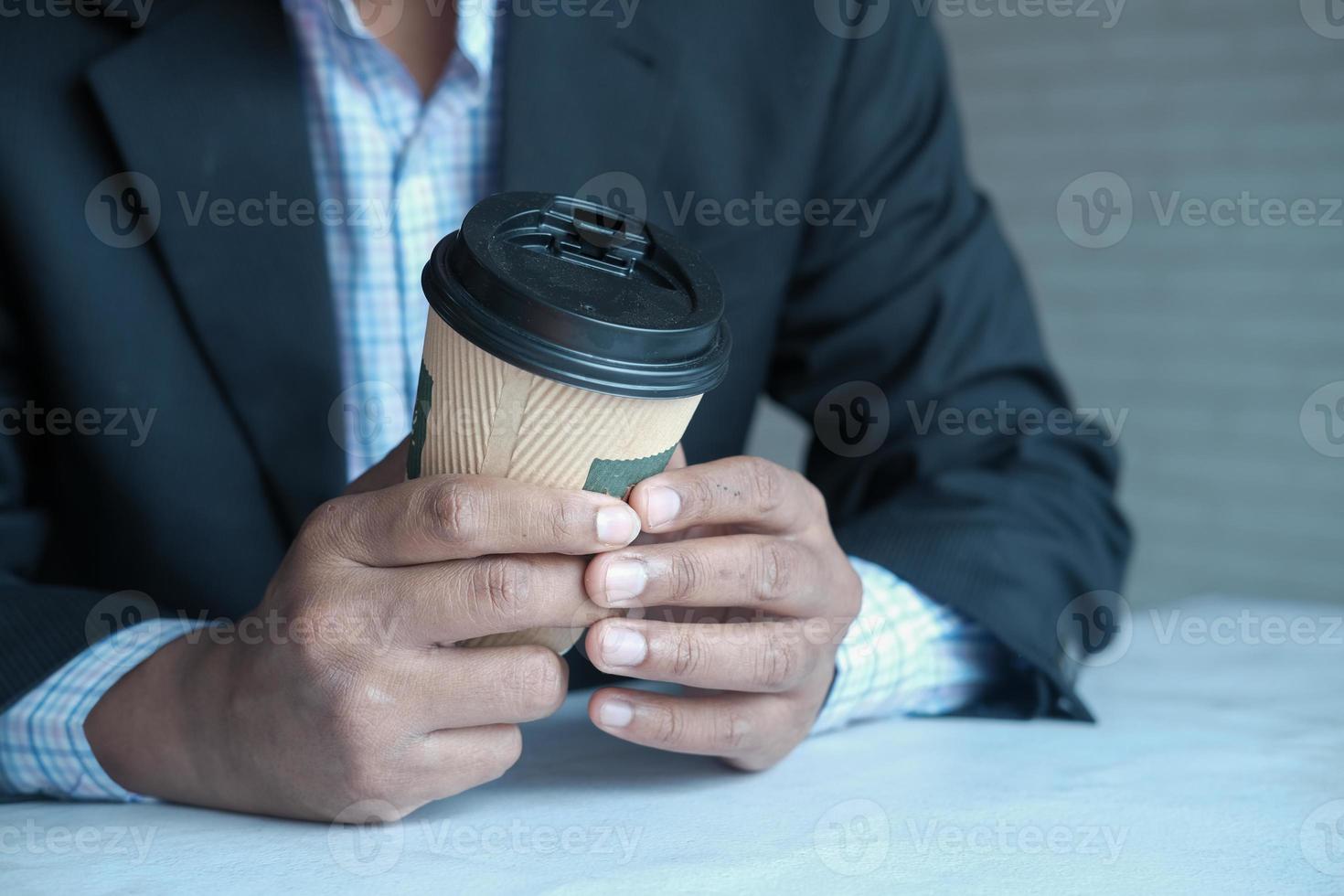 mano dell'uomo d'affari che tiene il bicchiere di carta da asporto sito bianco foto