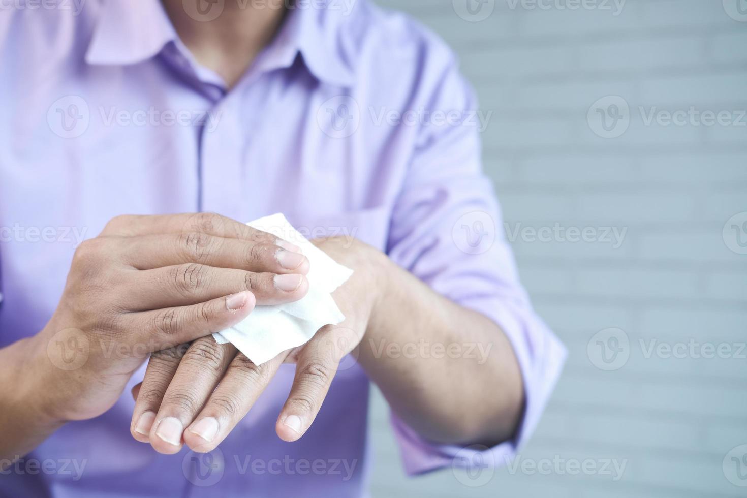 uomo che si disinfetta le mani con un panno umido foto