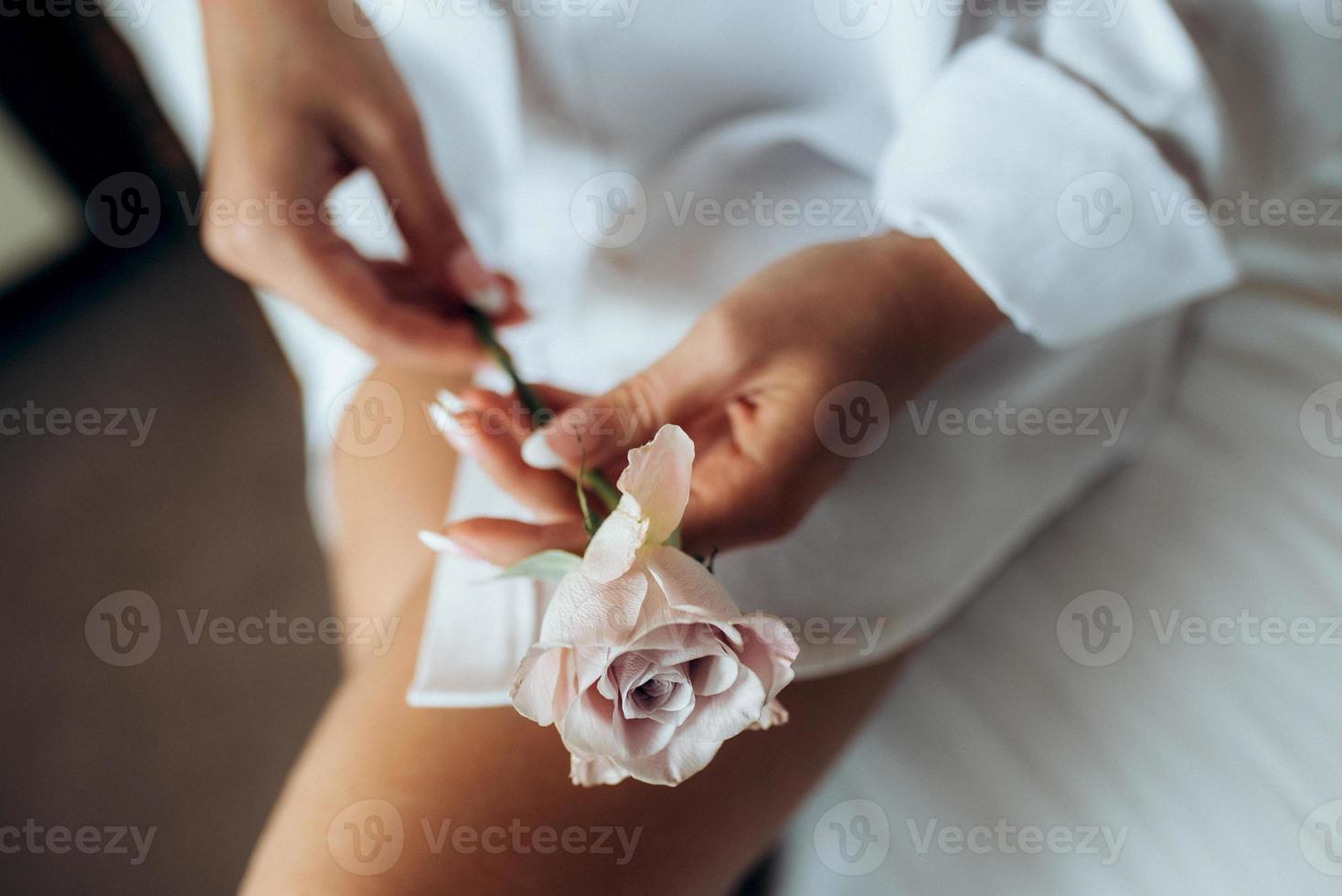 ragazza in camicia bianca tiene una rosa tra le mani foto