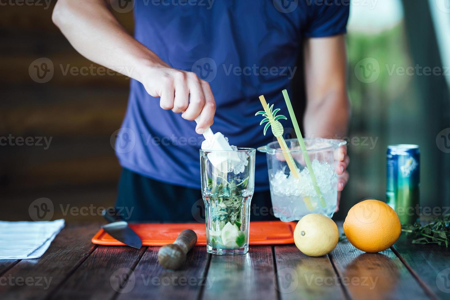 barman prepara cocktail alcolici di frutta a base di lime, menta, arancia, soda foto