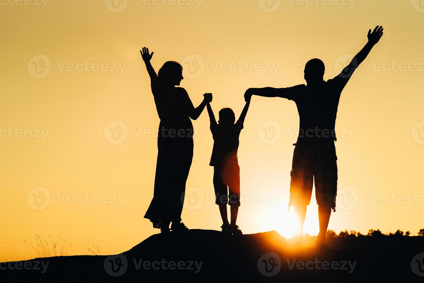 sagome di una giovane famiglia felice felice contro un tramonto arancione foto