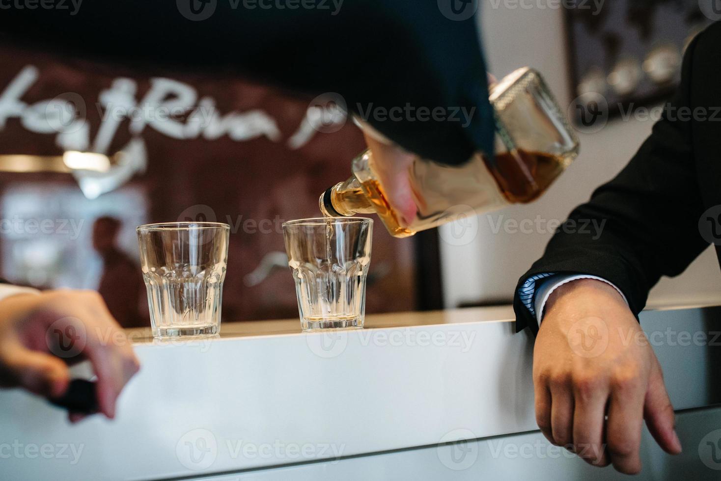 due ragazzi al bar bevono whisky da bicchieri di cristallo foto
