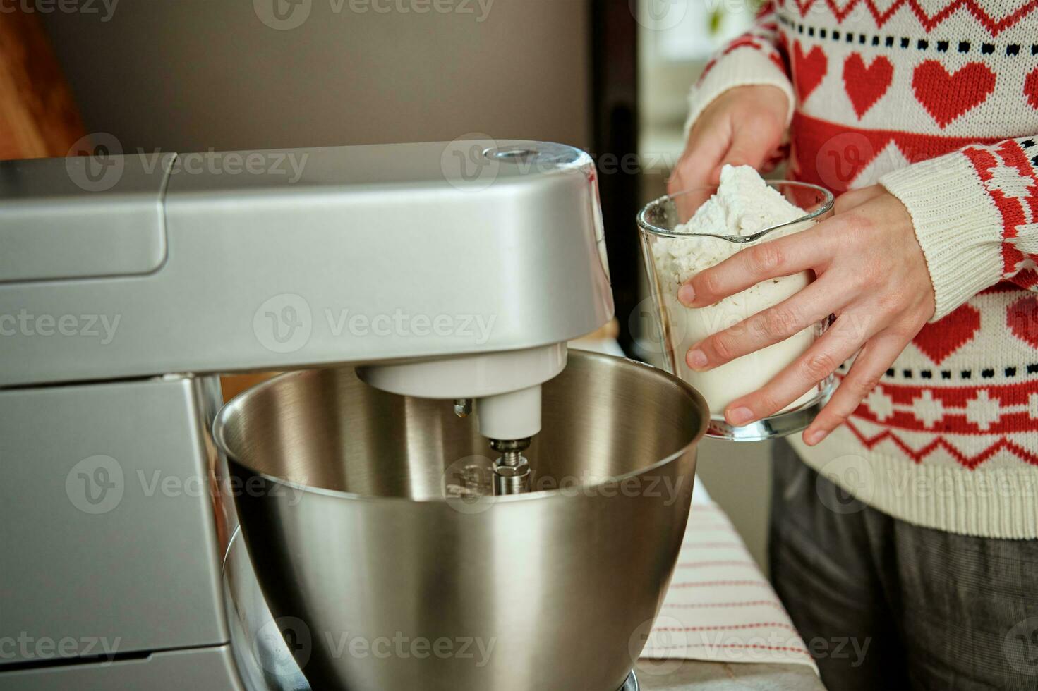 donna cucinando a casa cucina, uso elettrico miscelatore per preparazione Impasto foto