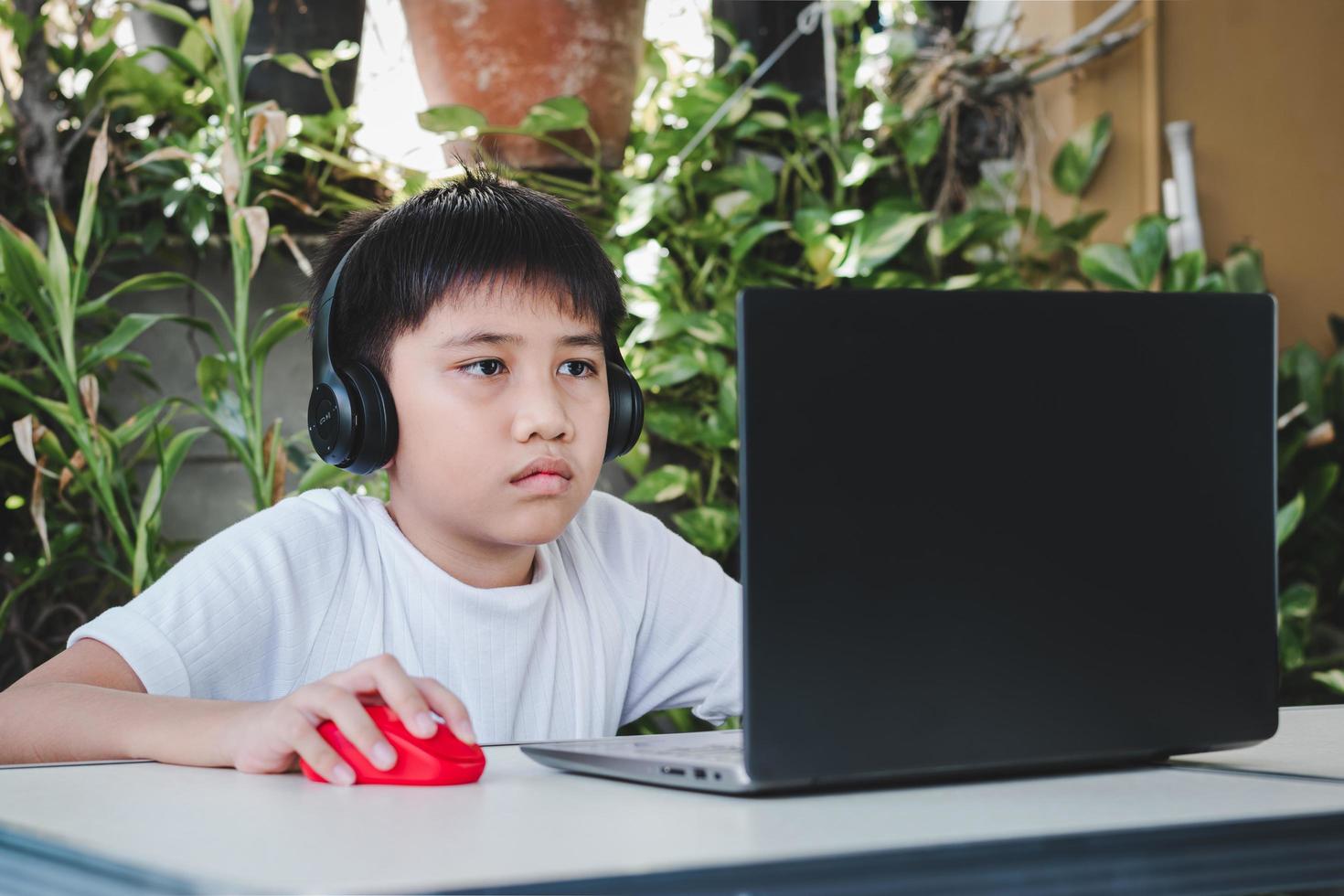 ragazzo asiatico indossa cuffie wireless e usa il computer portatile per studiare online foto