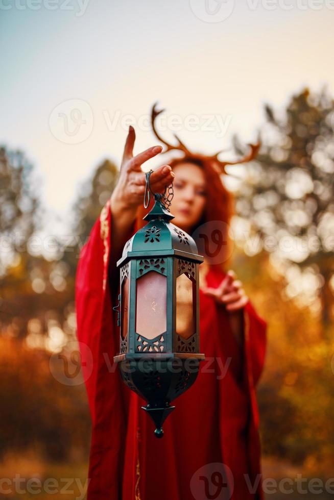 donna in abito lungo rosso con corna di cervo foto