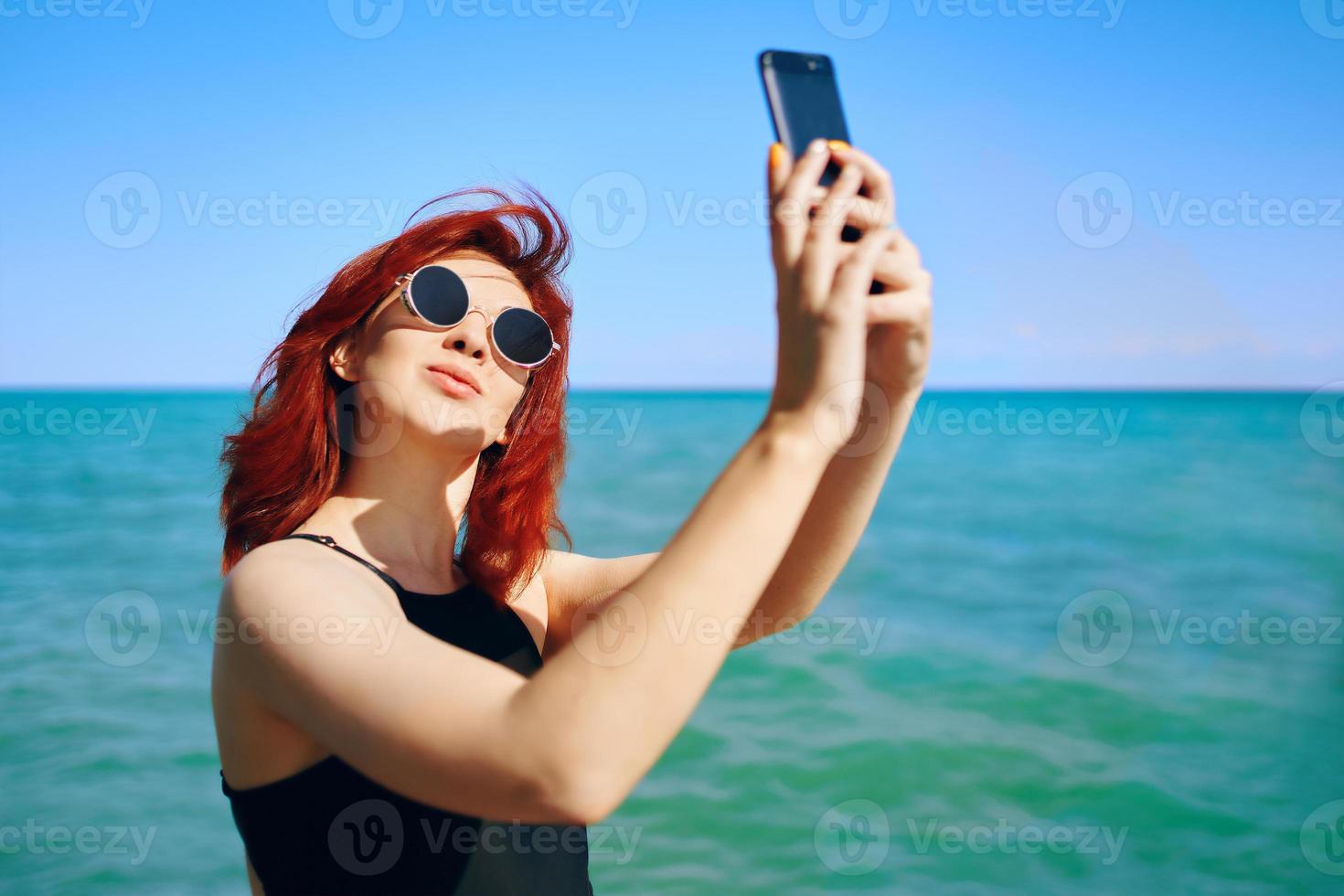 donna dai capelli rossi prende selfie sulla fotocamera dello smartphone foto