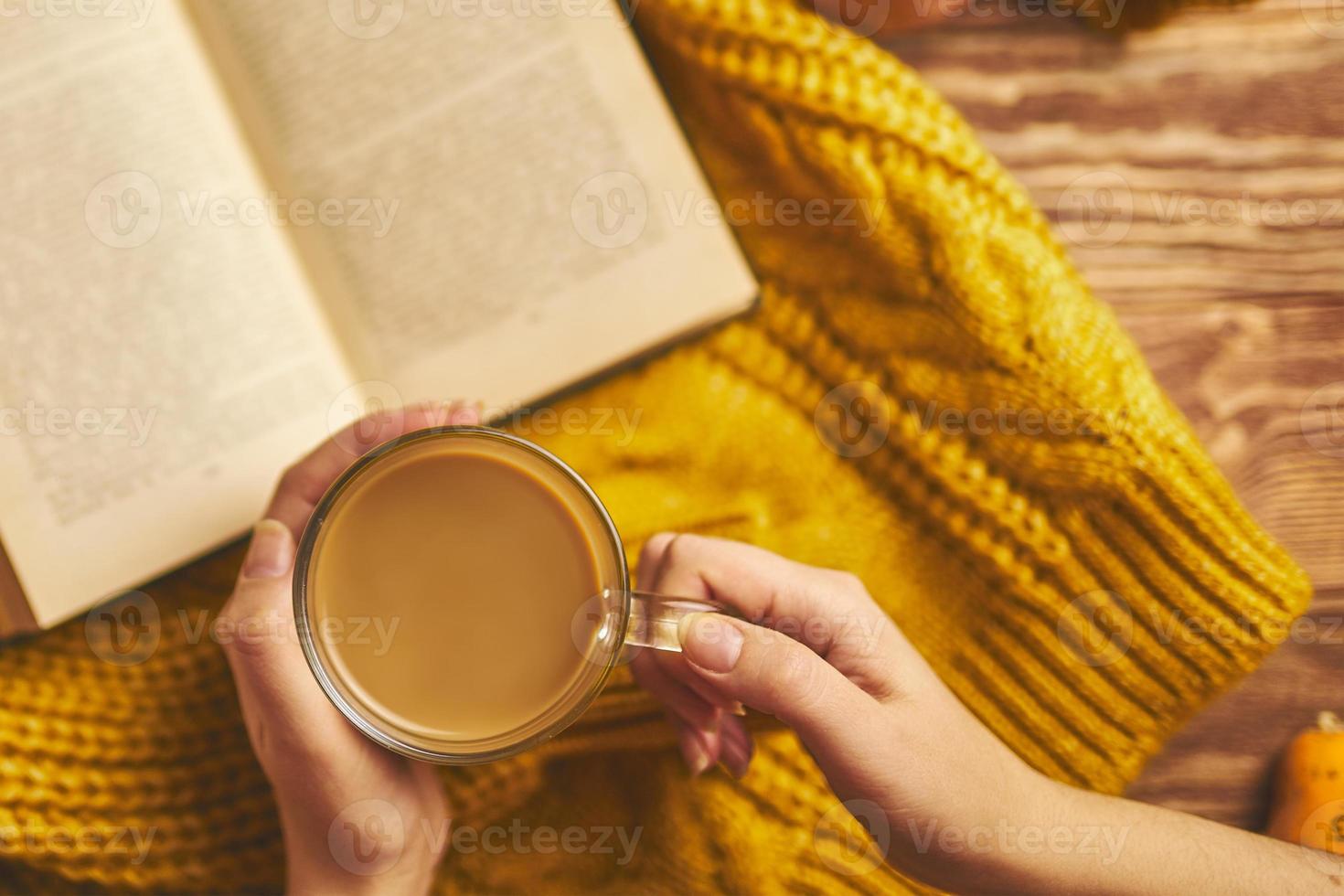 tazza di caffè, giacca a maglia accogliente e libro aperto su tavola di legno. foto