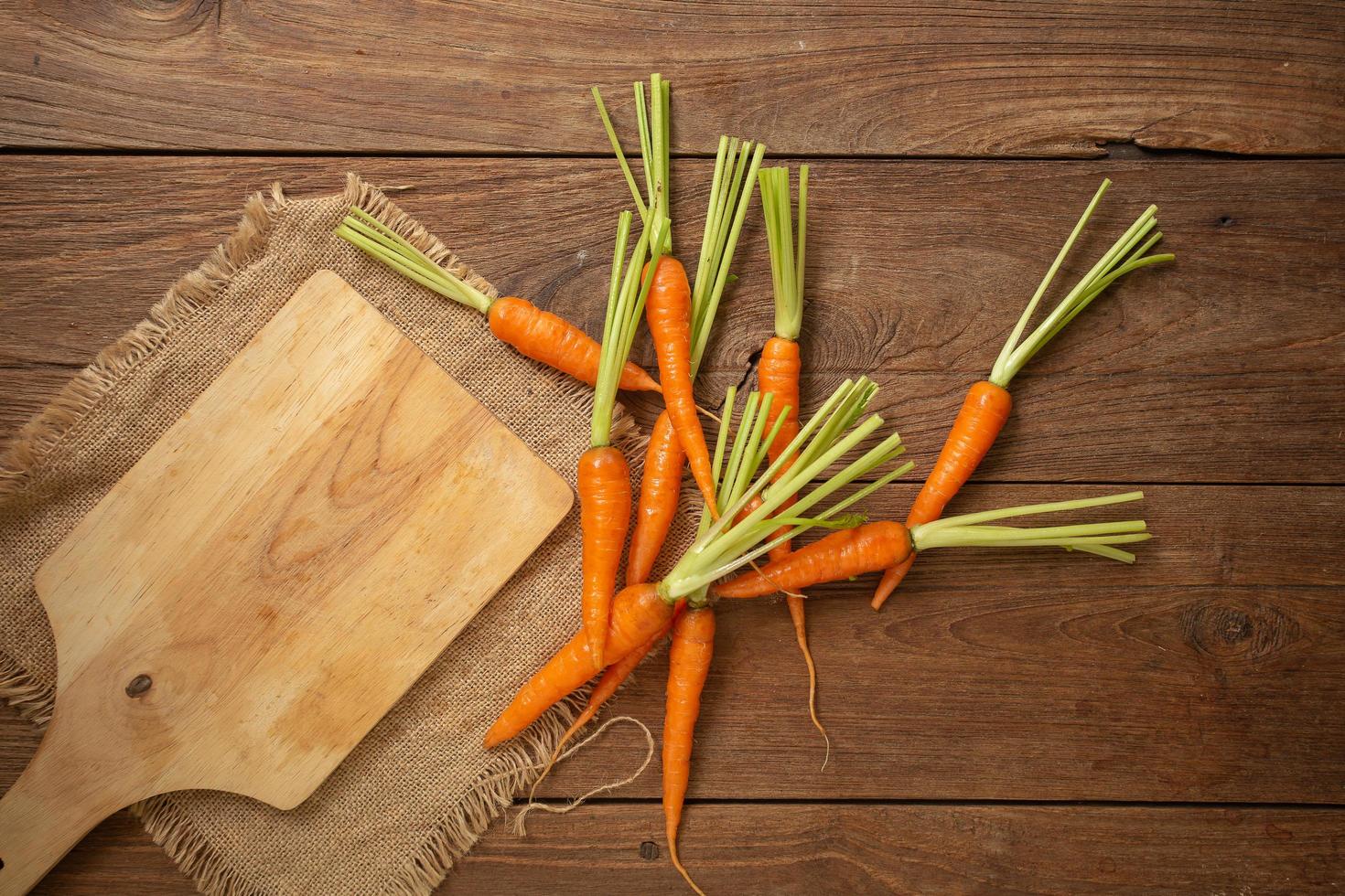 carotine fresche su tagliere di legno e fondo in legno foto