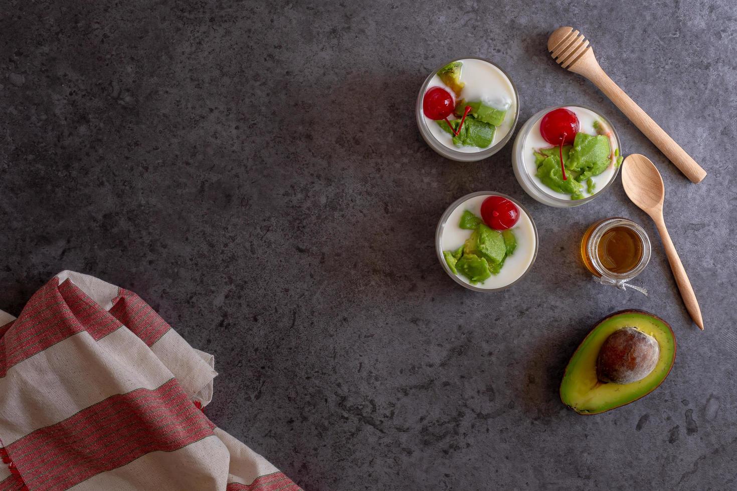 bicchiere di ciliegia e avocado affettati in yogurt su fondo in legno foto