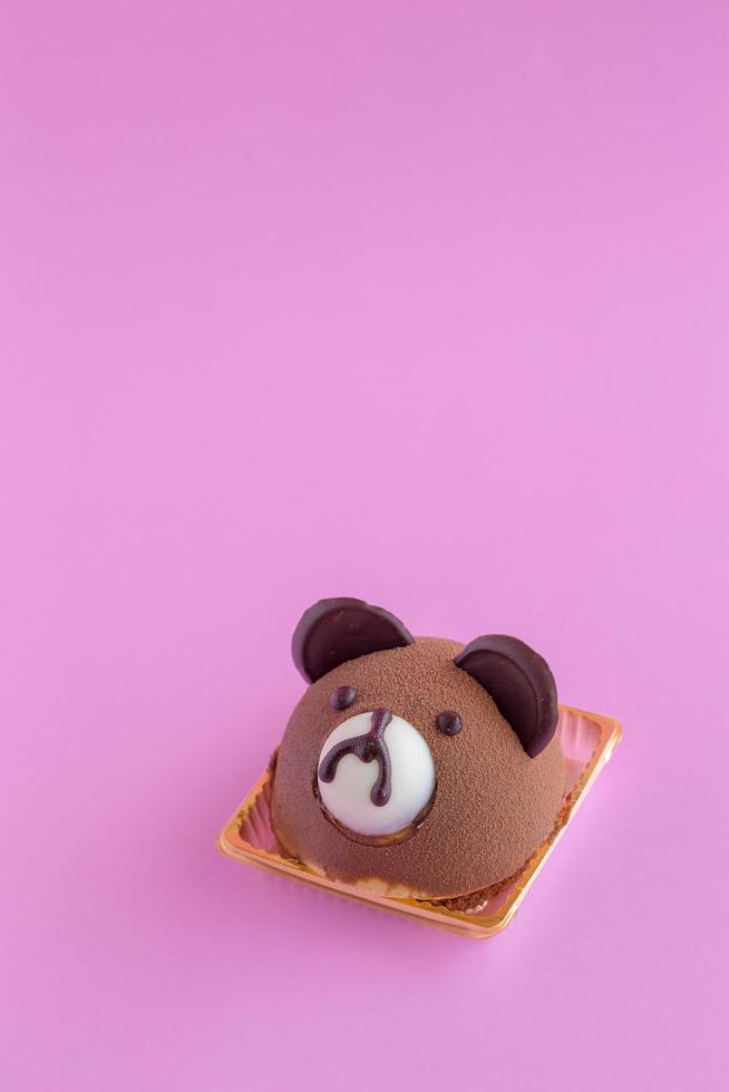 Torta di chiffon al cioccolato con testa di orsacchiotto marrone su sfondo rosa e spazio di copia foto