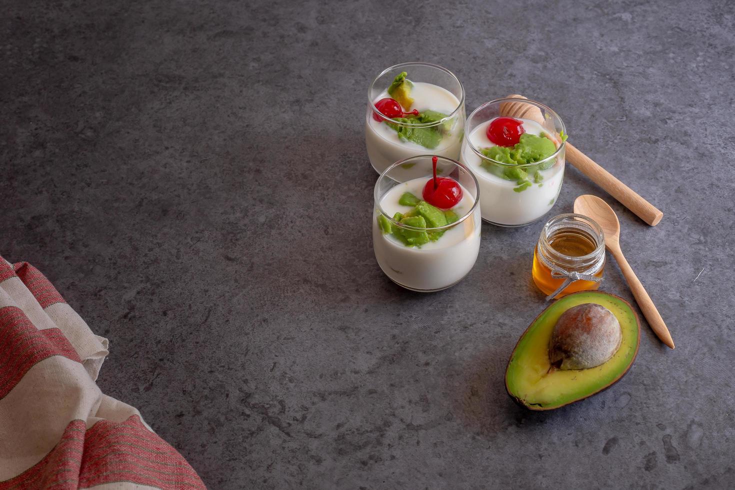 bicchiere di ciliegia e avocado affettati in yogurt su fondo in legno foto