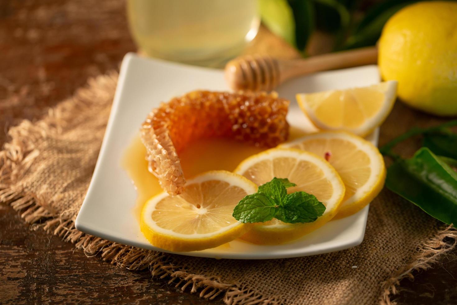 succo di limone con miele su tavola di legno, limoni e foglie di salvia foto