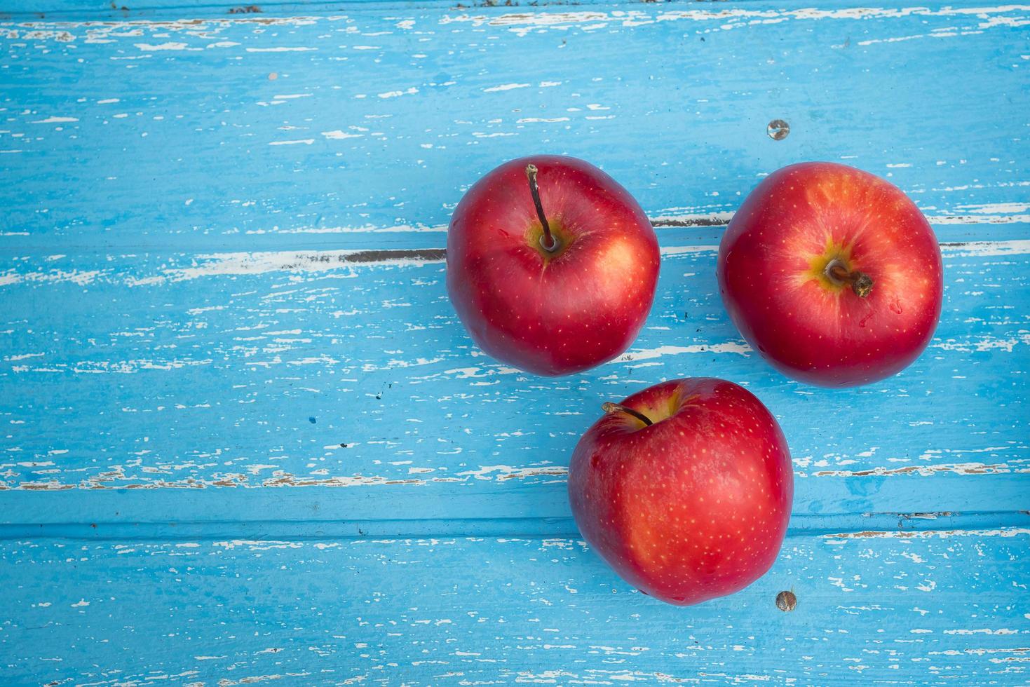 mele rosse su uno sfondo di tavolo in legno foto