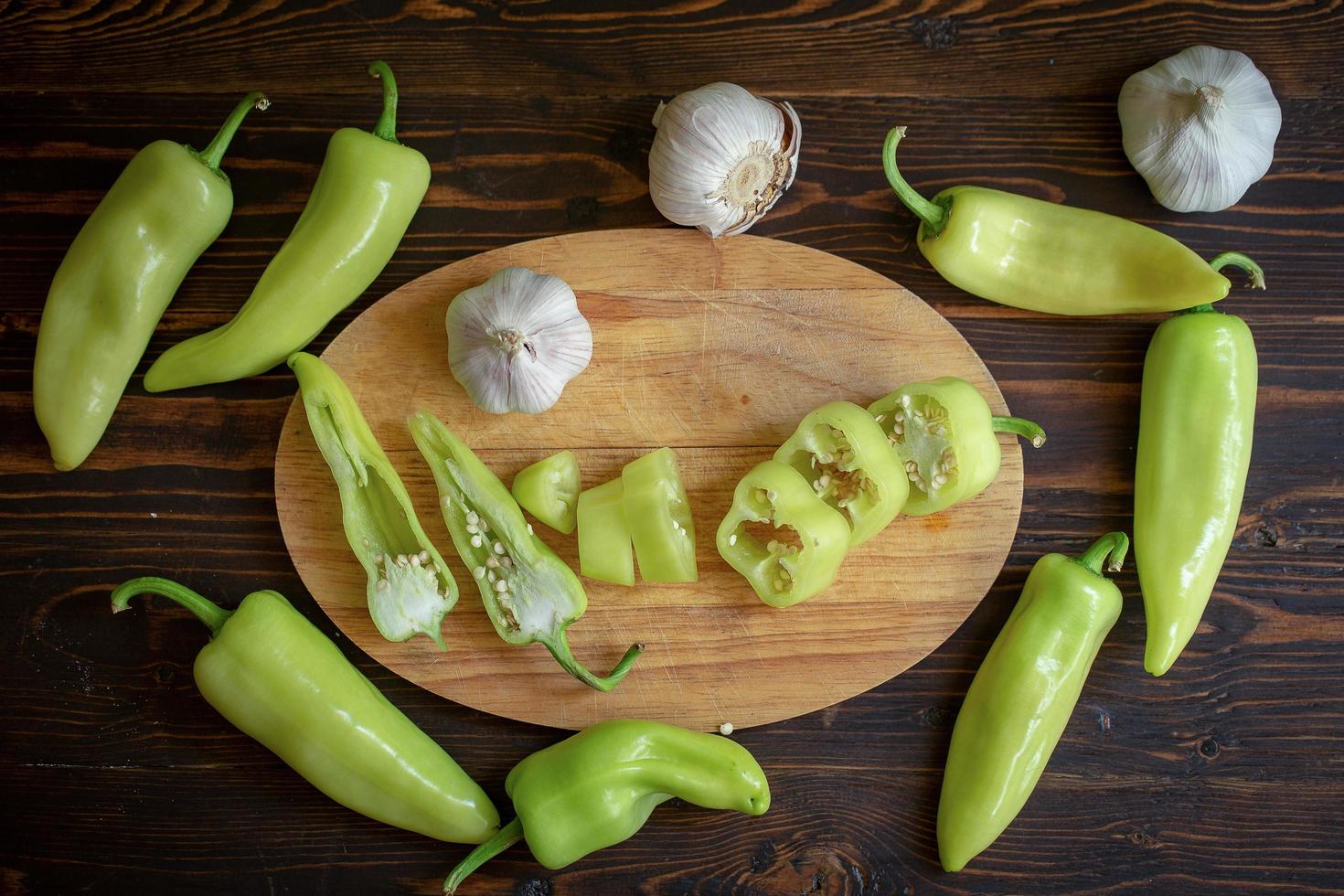 peperoncini piccanti verdi e peperoncino affettato con aglio su fondo di legno foto
