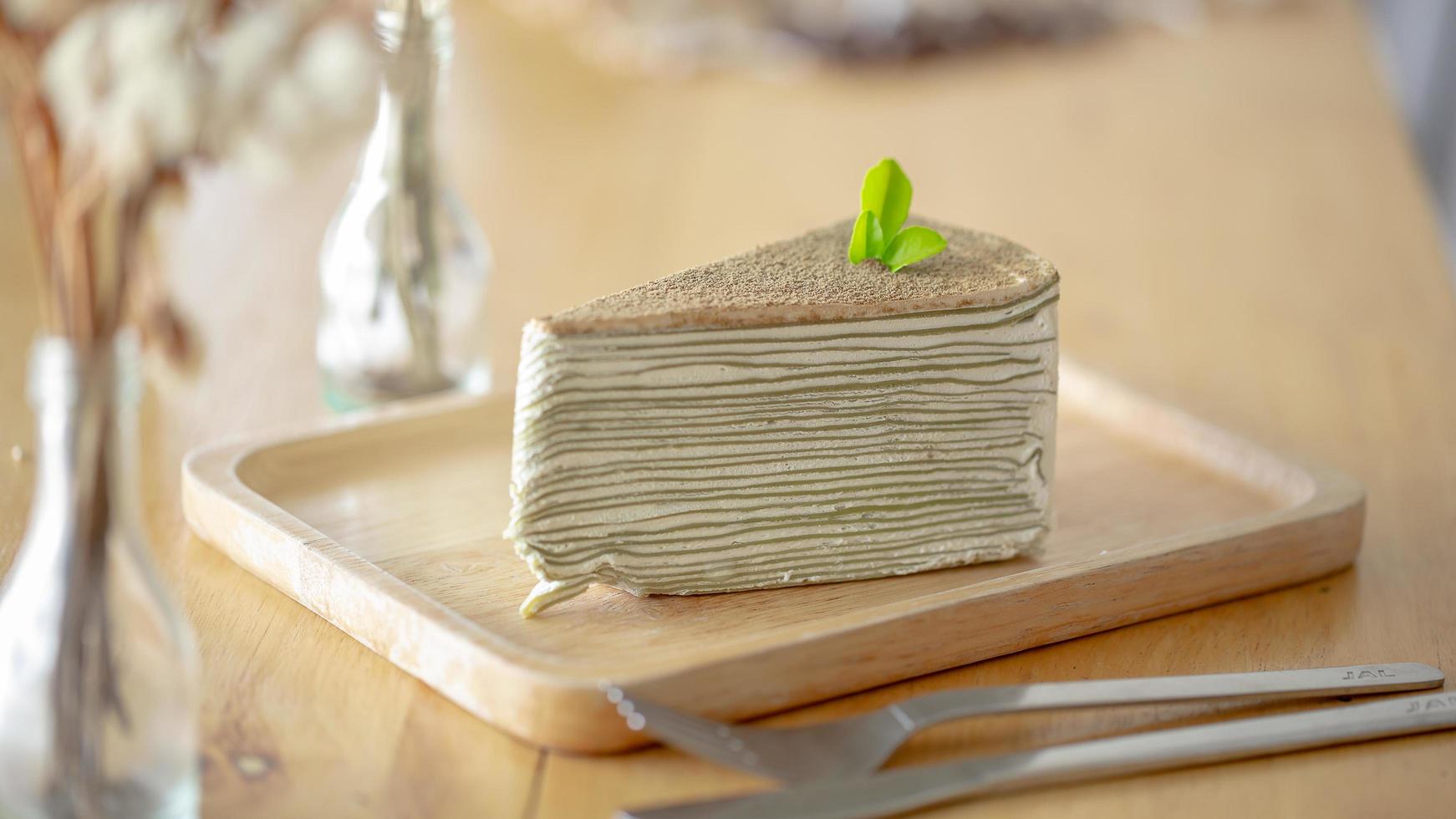 torta di crepe al tè verde con foglia di tè verde su piatto di legno foto