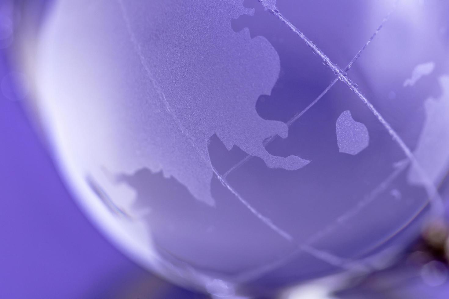 il globo è fatto di vetro su uno sfondo viola. globo di vetro. concetto di globalizzazione foto