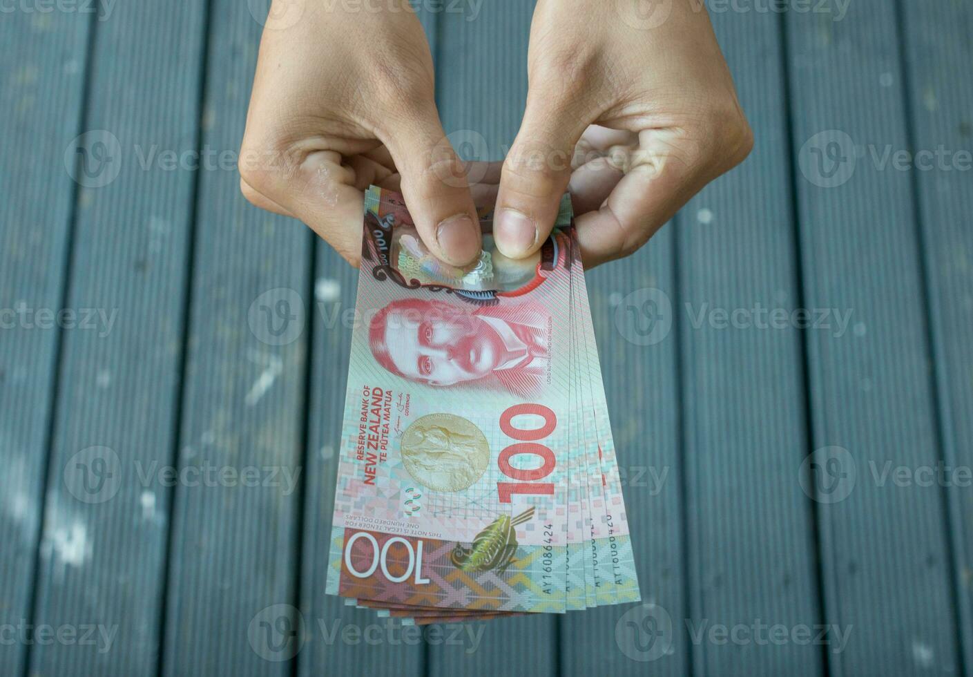 ritagliata tiro Visualizza di qualcuno mostrando il i soldi nuovo Zelanda 100 dollari. foto