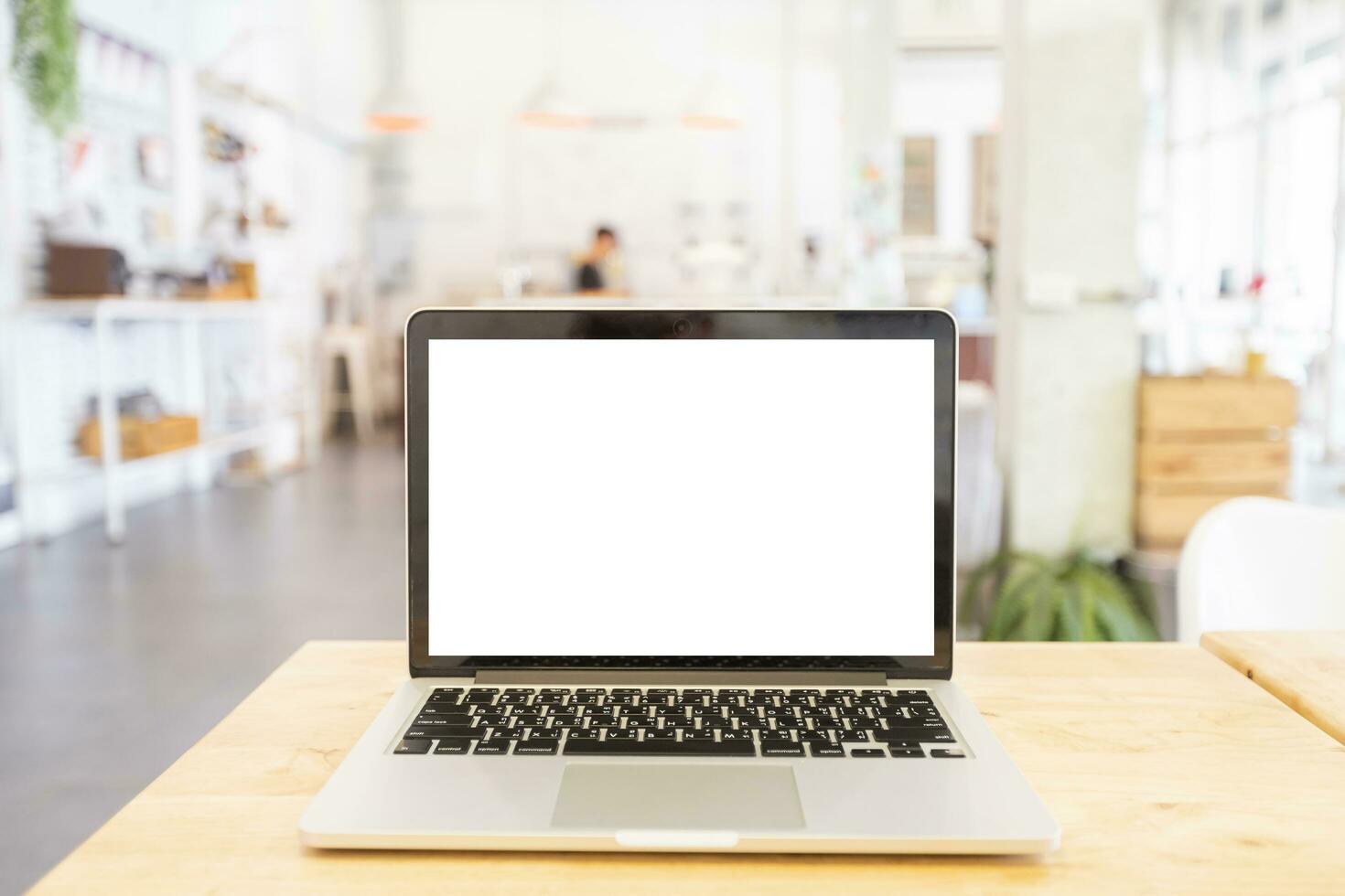 modello Immagine di il computer portatile con vuoto bianca schermo su di legno tavolo di nel il caffè negozio. foto