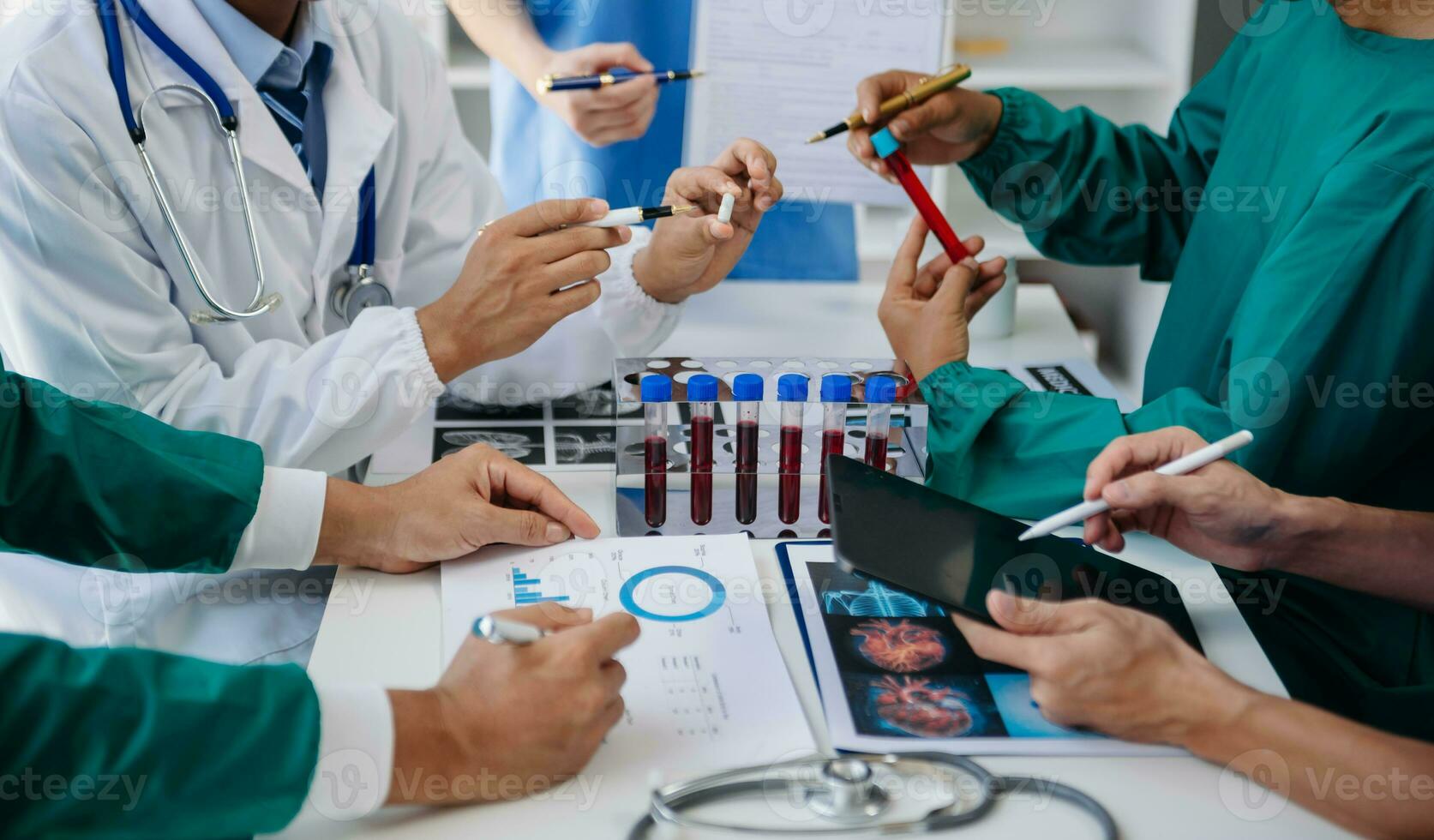 medico squadra avendo un' incontro con medici nel bianca laboratorio cappotti e chirurgico scrub seduto a un' tavolo discutere un' pazienti Lavorando in linea utilizzando computer nel il medico industria foto