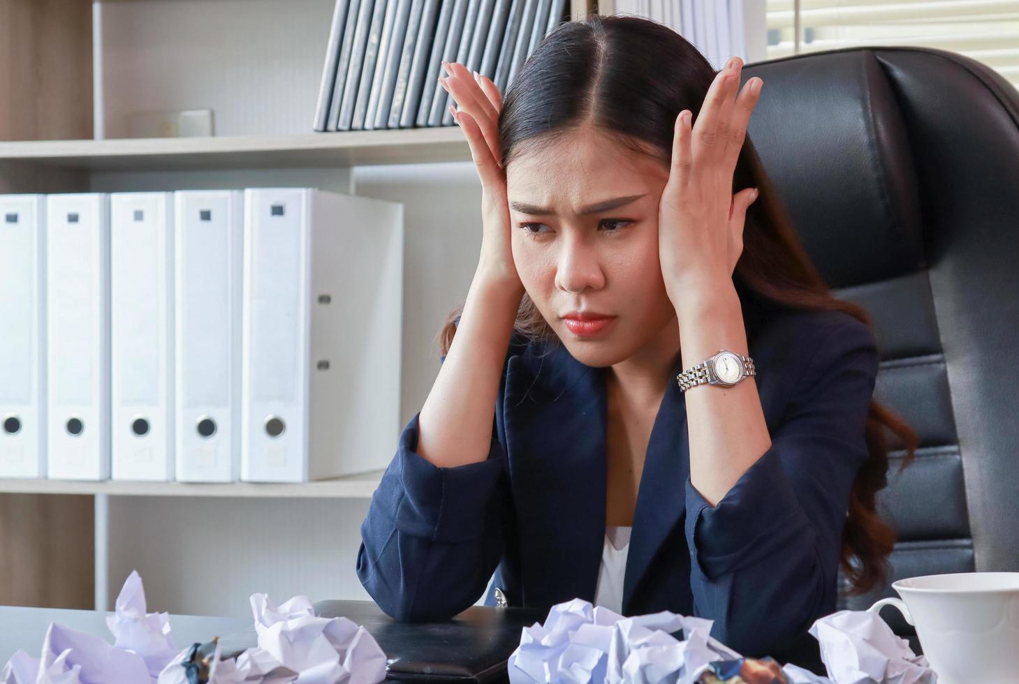 donna d'affari asiatica seduta in ufficio con lo stress le donne non sono felici al lavoro foto