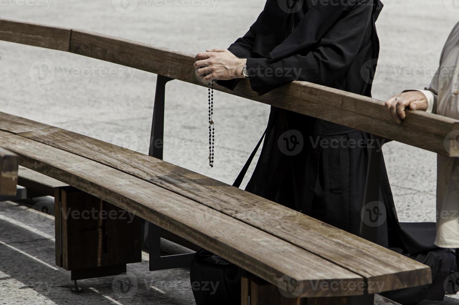 mani di un sacerdote con una croce in preghiera foto