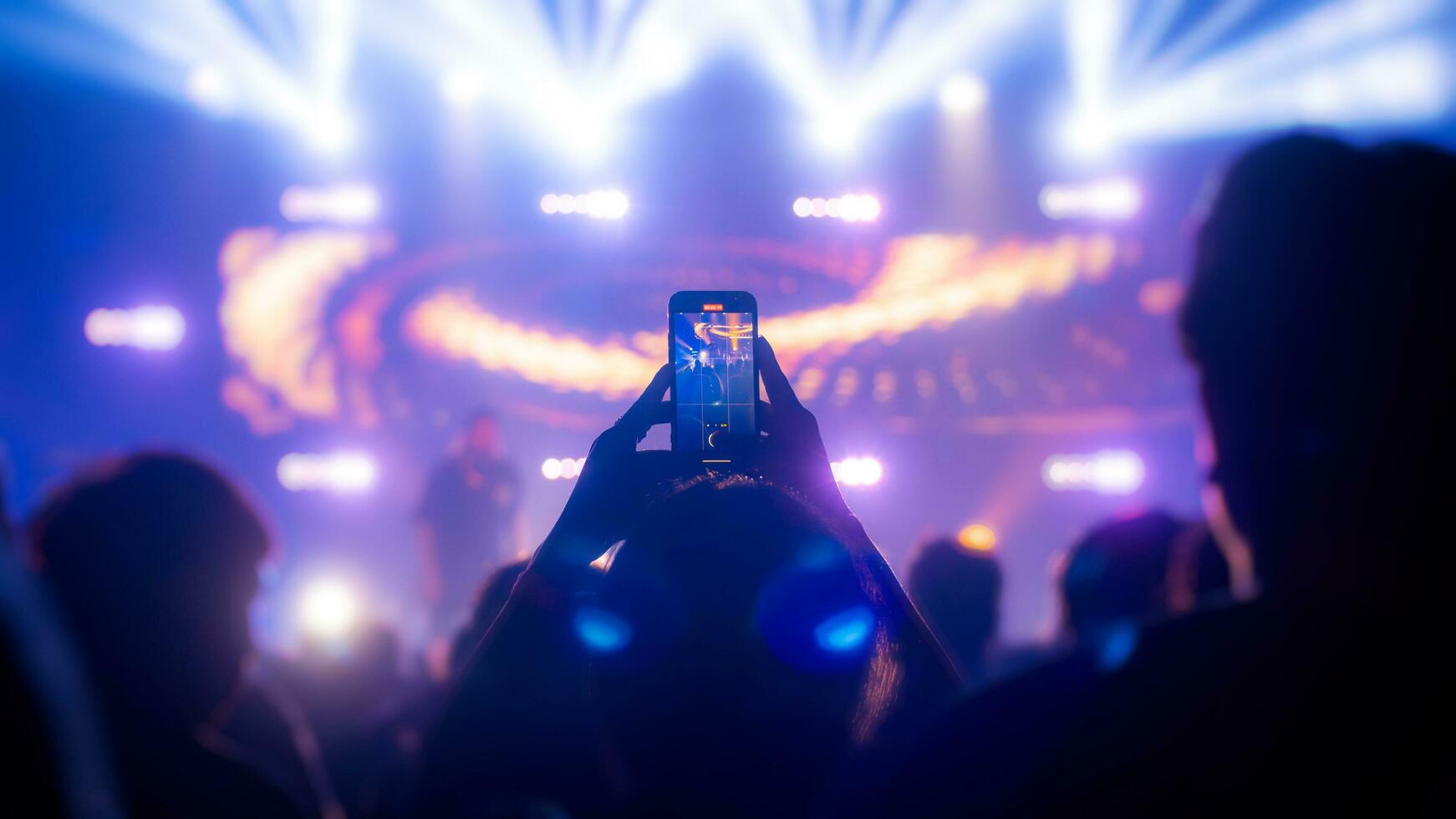 persone Tenere inteligente Telefono e registrazione e Fotografare nel concerto , silhouette di mani con mobile , evento sfondo concetto foto