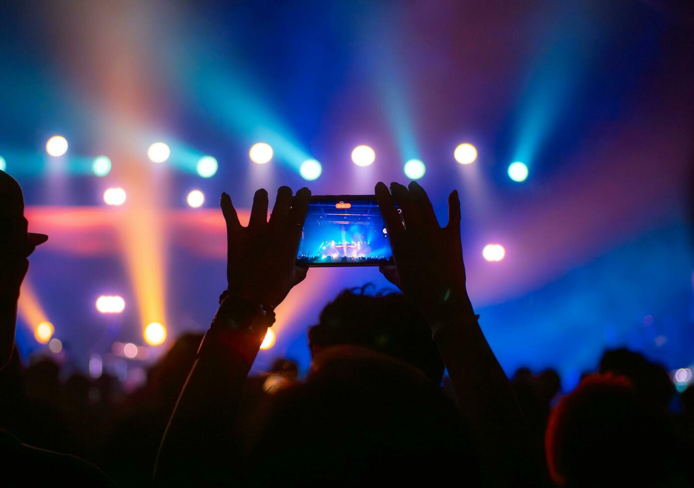 persone Tenere inteligente Telefono e registrazione e Fotografare nel concerto , silhouette di mani con mobile , evento sfondo concetto foto