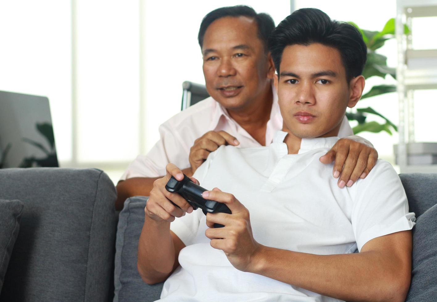 padre e figlio che giocano felicemente ai videogiochi a casa in vacanza foto