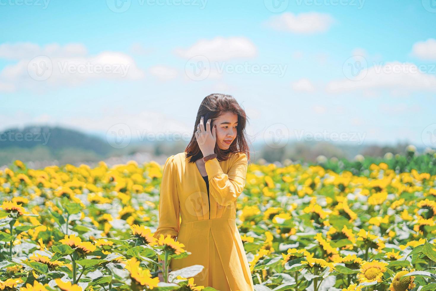 donna asiatica gioiosa con un bellissimo campo di girasoli, concetto di viaggio estivo foto