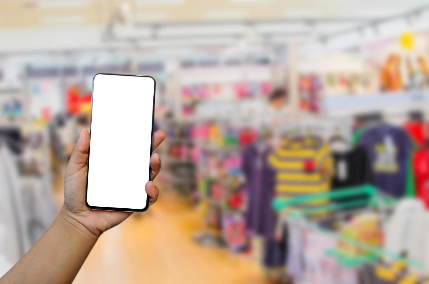 schermo vuoto dell'immagine del modello del telefono della tenuta della mano per il testo pubblicitario nel fondo del centro commerciale del supermercato foto