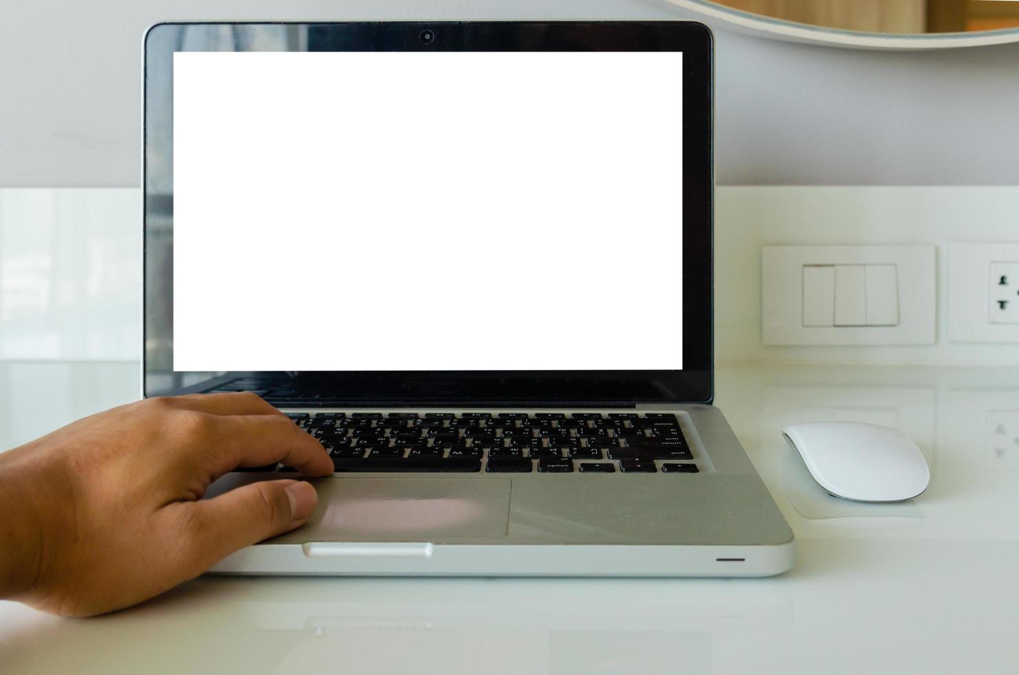 mano sulla tastiera computer portatile mock up e mouse schermo vuoto bianco per testo pubblicitario sul tavolo foto