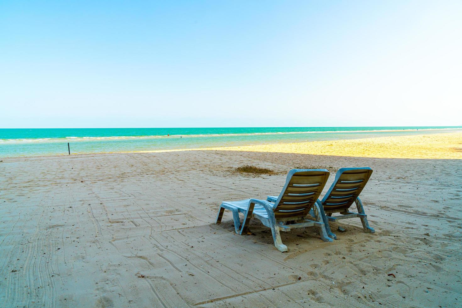 sedia a sdraio vuota sulla sabbia con lo sfondo del mare oceano foto