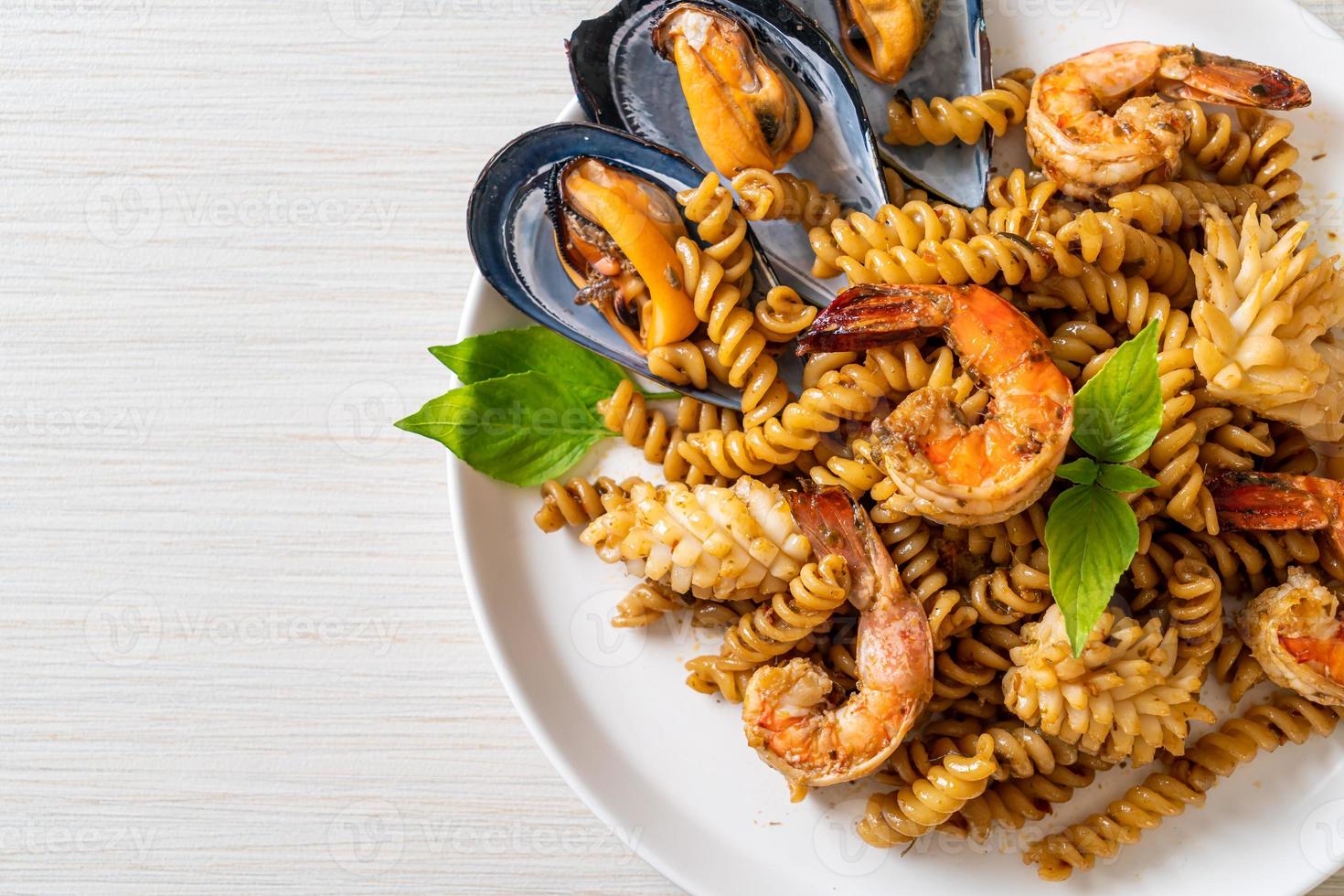 pasta a spirale saltata in padella con salsa di frutti di mare e basilico - stile fusion foto