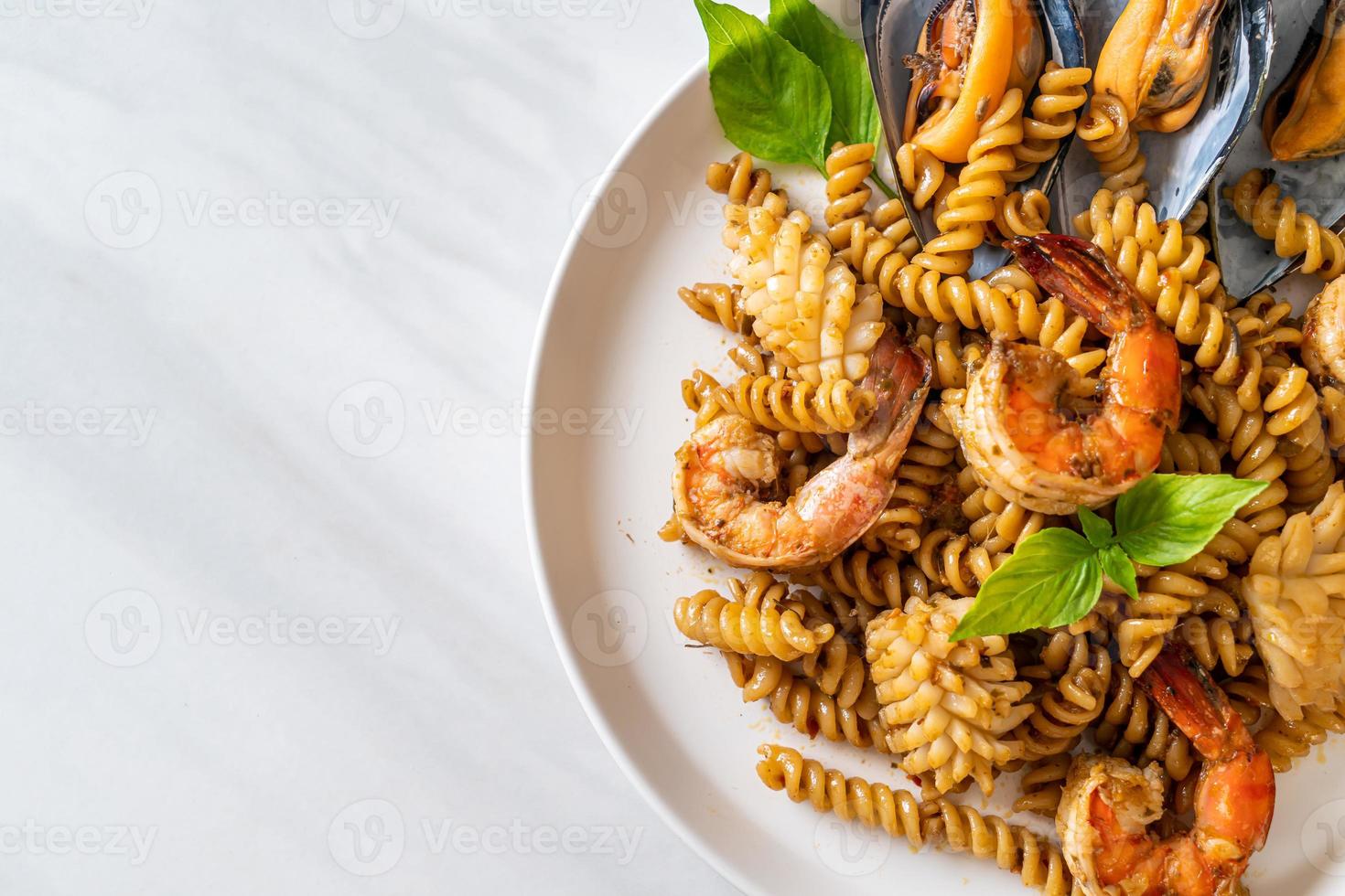 pasta a spirale saltata in padella con salsa di frutti di mare e basilico - stile fusion foto