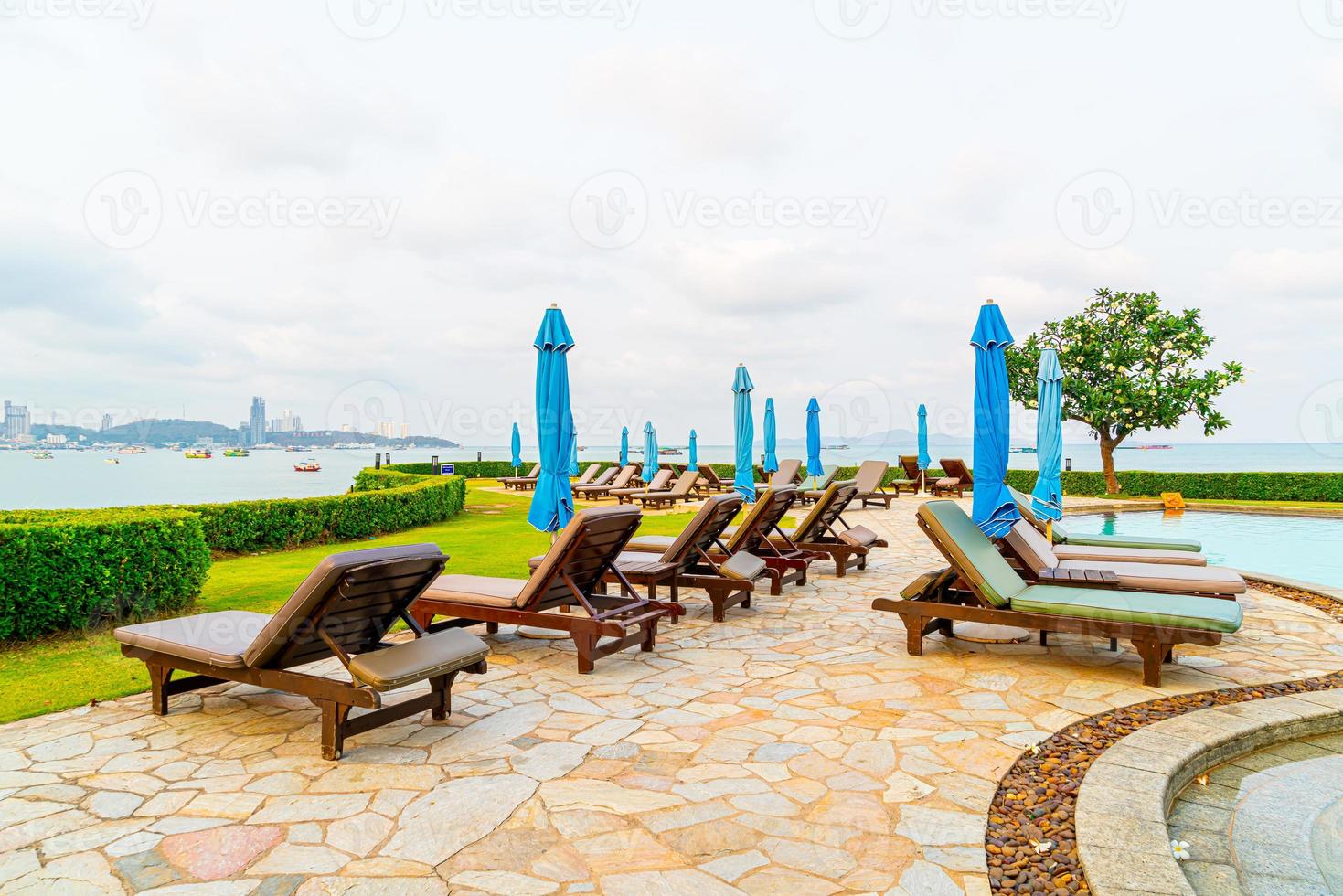 piscina con sedia o piscina per lettino e ombrellone intorno alla piscina con sfondo di spiaggia del mare a pattaya in thailandia foto