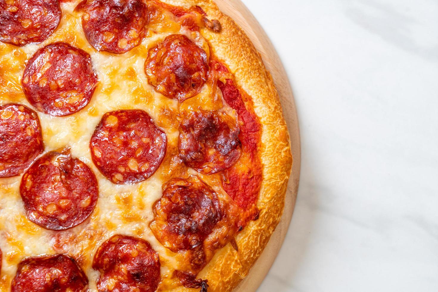 pizza ai peperoni su vassoio di legno - stile alimentare italiano foto