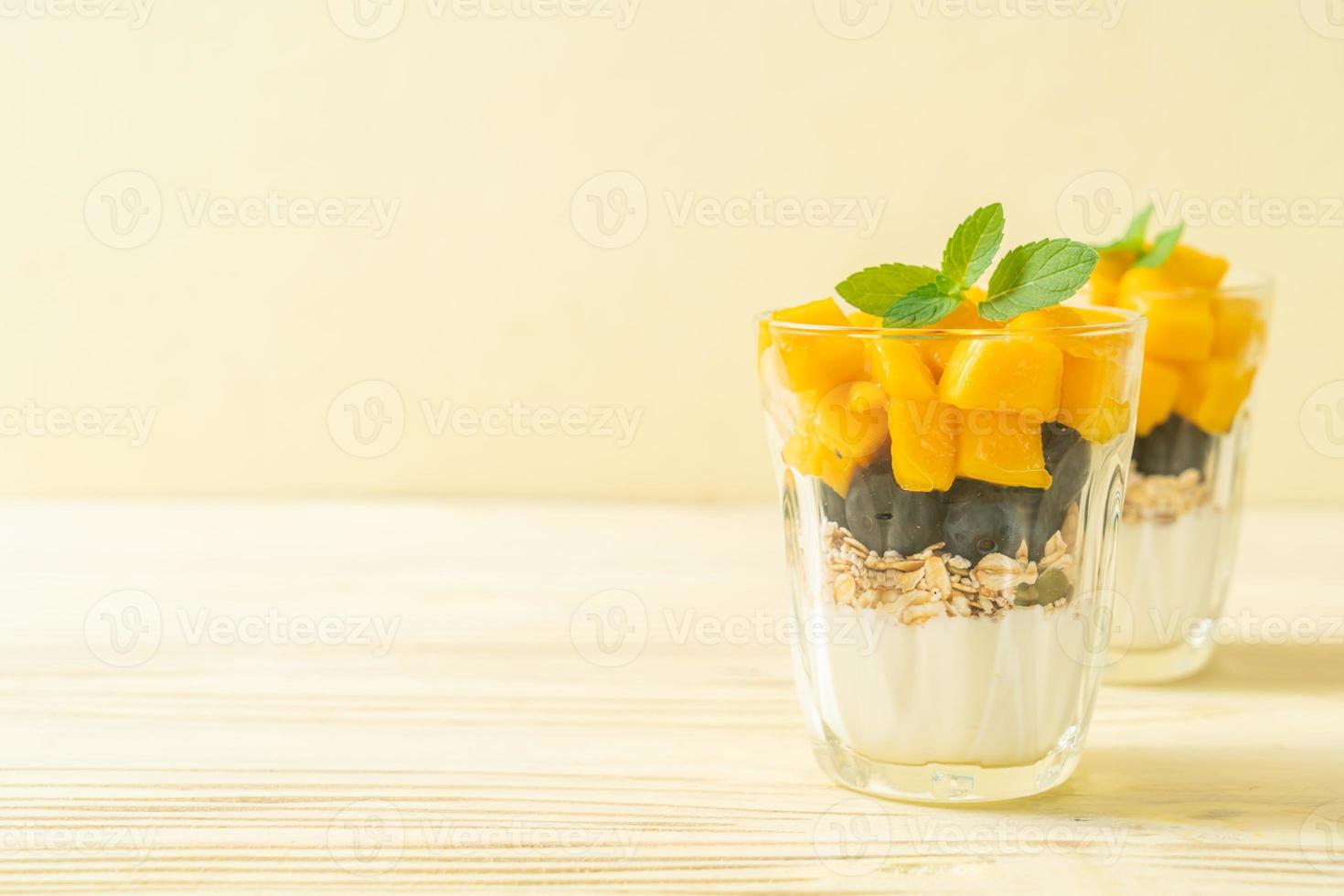 mango fresco fatto in casa e mirtillo fresco con yogurt e muesli - stile alimentare sano healthy foto