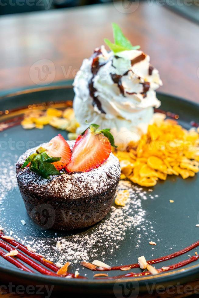 torta al cioccolato lava con gelato alla fragola e vaniglia su banda nera foto