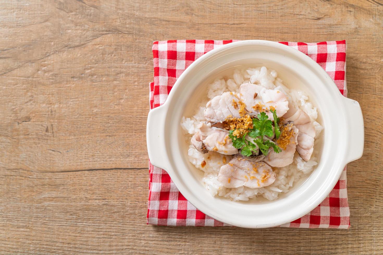 zuppa di porridge o riso bollito con scodella di pesce foto