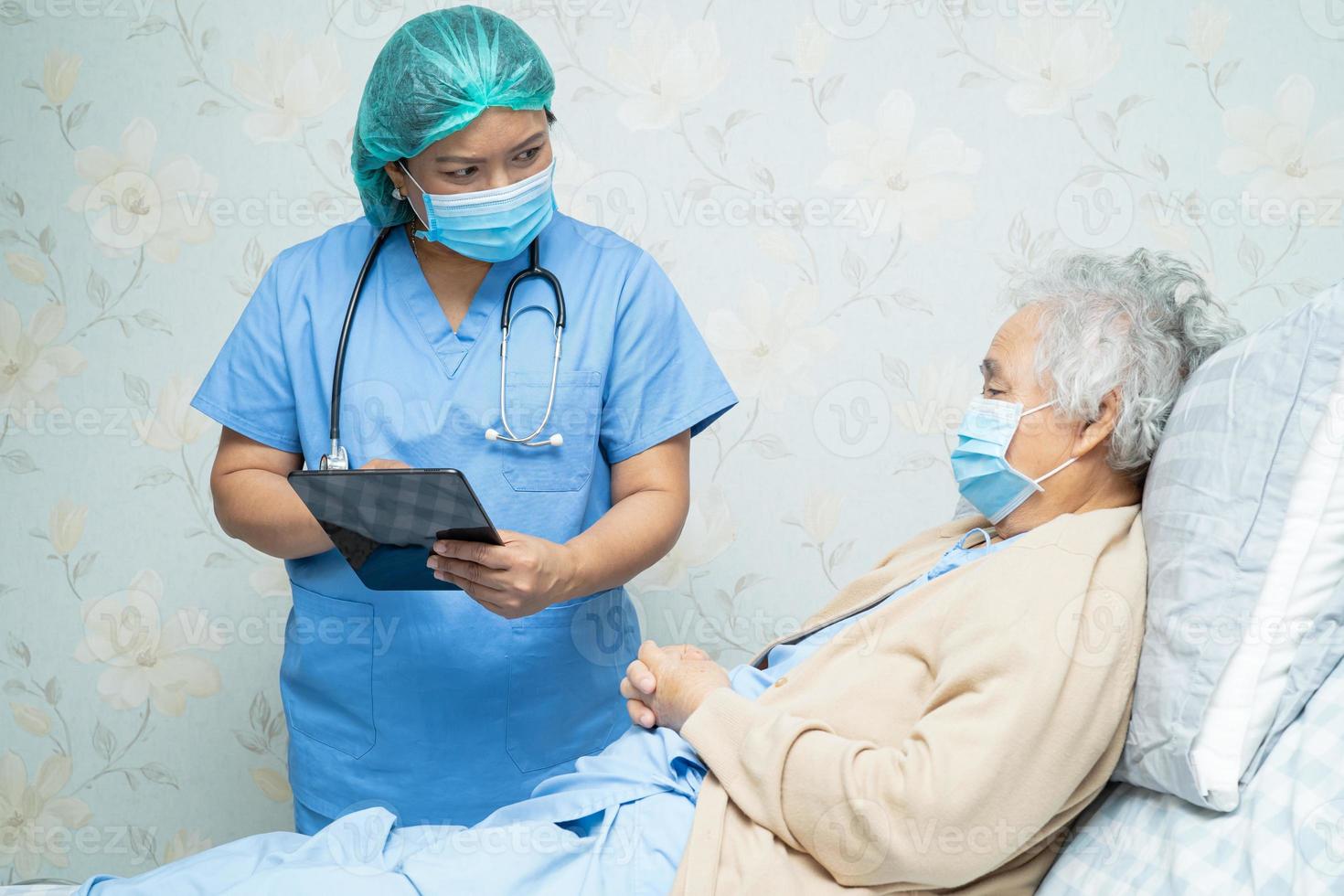 medico asiatico che indossa visiera e tuta in dpi e tiene in mano un tablet nuovo normale per controllare il paziente proteggere la sicurezza infezione covid-19 focolaio di coronavirus nel reparto ospedaliero di quarantena. foto