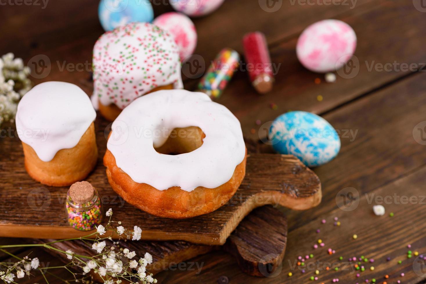 torte festive con glassa bianca, noci e uvetta con uova di Pasqua sulla tavola festiva foto