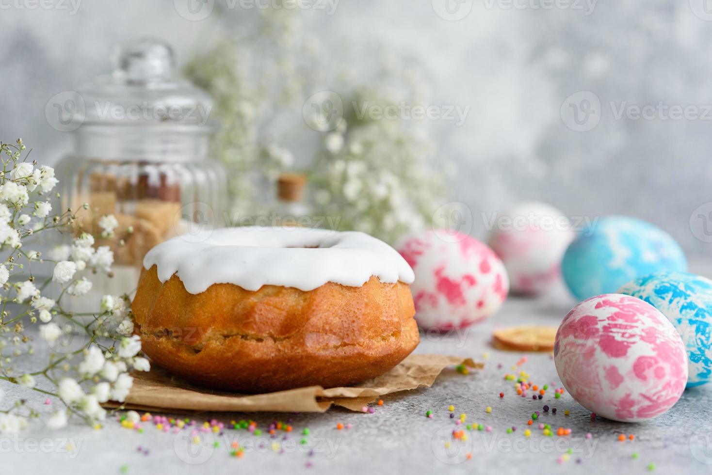 torte festive con glassa bianca, noci e uvetta con uova di Pasqua sulla tavola festiva foto